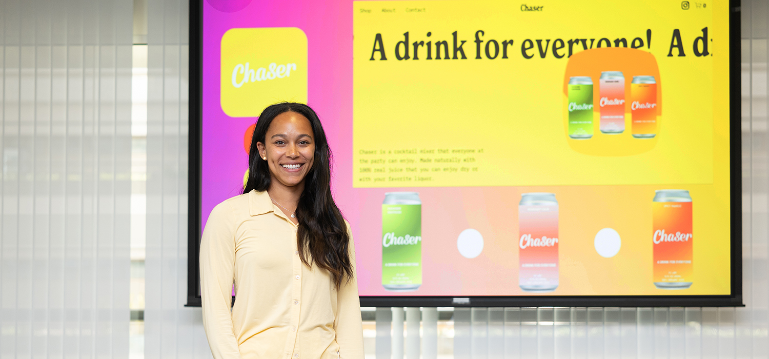 A student standing in front of a projection screen displaying her branding for her new business, Chaser.